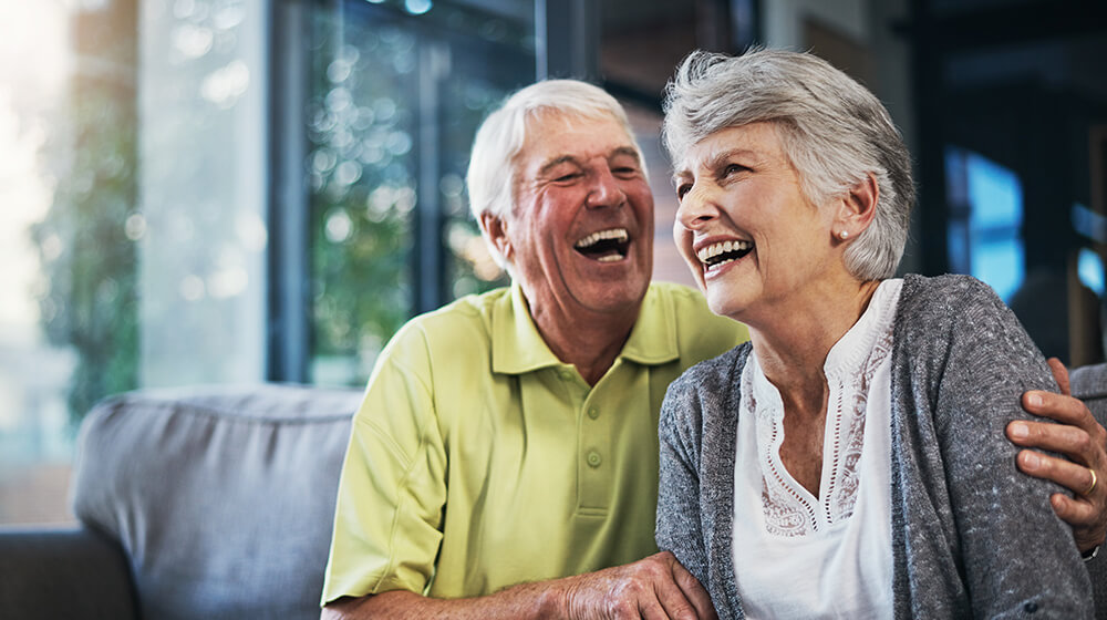 elderly man in green polo hugs and laughs with wife
