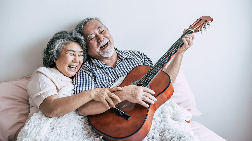 Elderly couple laugh and enjoy their favorite music on guitar