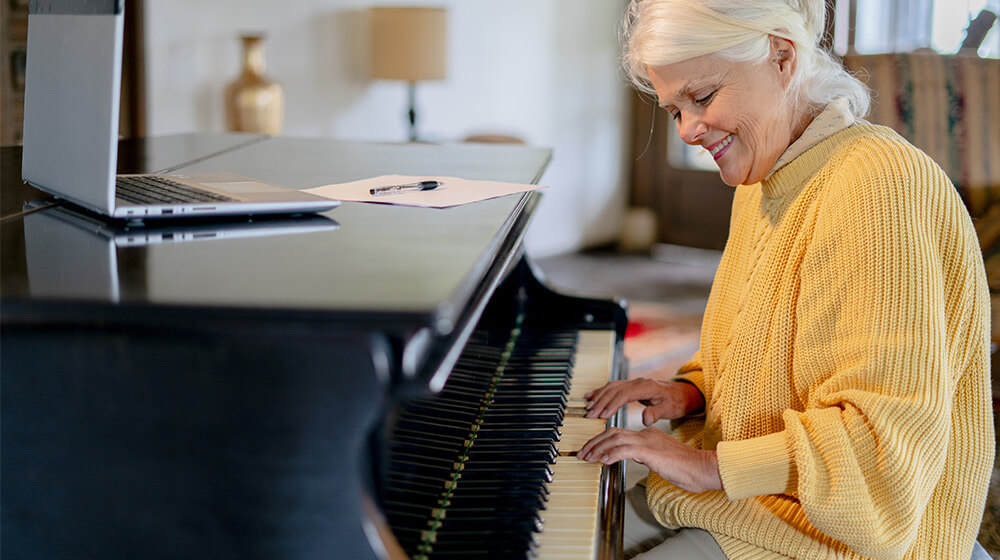 Mature woman smiles while sitting at piano playing tune in living room