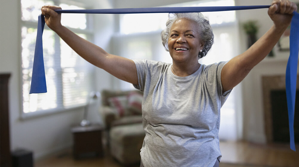 Woman in exercise class smiles and uses stretch band