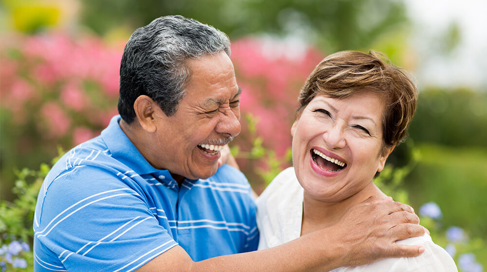 Hispanic couple laughs in scenic meadow