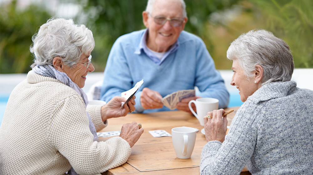 Group of elderly residents play a game of cards in nice outdoor weather