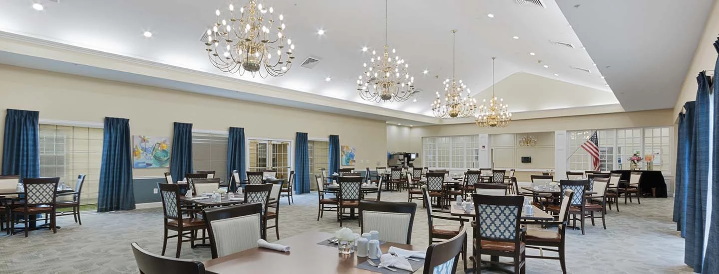 Interior dining room of ACOYA Mesa with high ceilings, bright modern chandeliers and elegant dining seating and tables in the room